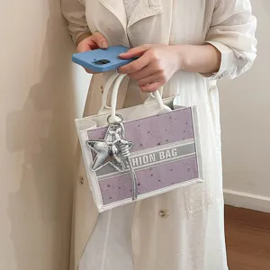 Chic star pattern canvas tote bag with stylish silver charms and top handles for women.