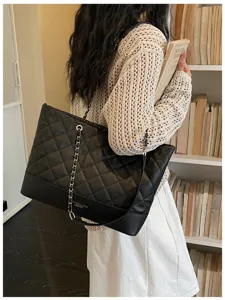 Nahaufnahme der schwarzen gesteppten Tasche mit Kette, Detailansicht im hellen Raum.