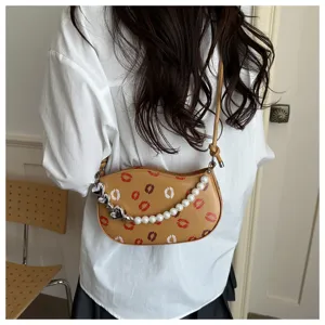 Vue détaillée d'un mini sac croissant chic avec imprimés baisers et chaînes de perles.