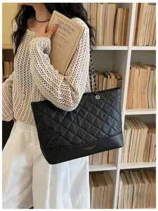 Detailansicht der schwarzen gesteppten Henkeltasche mit Kette vor stilvoller Kulisse.
