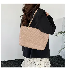 Vista dettagliata della elegante borsa tote trapuntata beige con catena indossata.