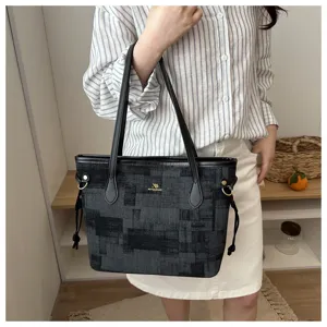 Nahaufnahme der stilvollen schwarzen Eimer Handtasche mit Muster und goldenem Logo.