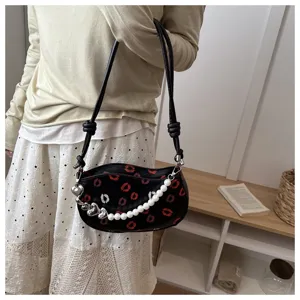 Vue détaillée du sac de selle miniature tendance pour femme avec imprimé lèvres et perles.