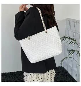 Dettaglio ravvicinato della borsa shopper trapuntata bianca con elegante tracolla a catena.