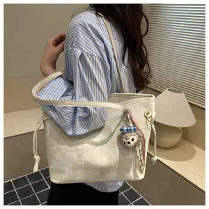 Detailansicht der modischen Eimerentasche mit niedlichem Plüschanhänger und Riemen.