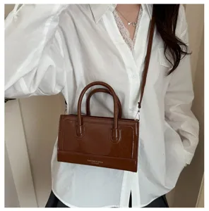 Detail view of brown patent leather mini crossbody bag, retro textured handbag for women.