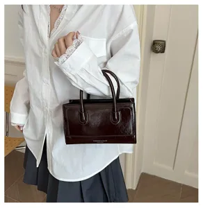 Detail view of vintage structured brown leather handbag with double top handles and chic design.