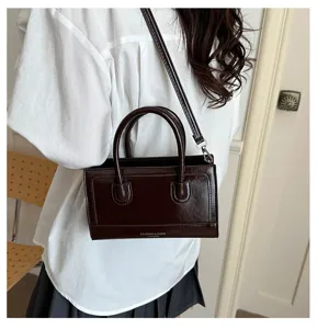 Detail view of a vintage dark brown leather crossbody bag with top handles, chic and stylish.