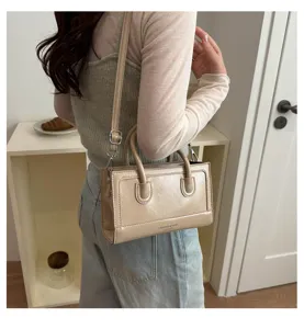 Detail shot of the stylish beige crossbody bag worn on shoulder, showing compact size.