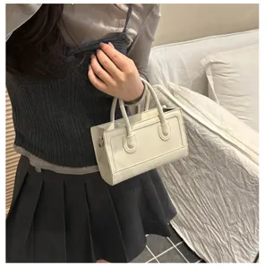 Detail view of a minimalist retro white PU leather mini handbag with top handles and chic stitching.