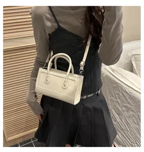 Close up detail of white mini handbag worn by model, showing clean modern minimalist style.