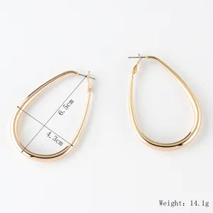 Dettagli di grandi orecchini a cerchio dorati a goccia, design ovale geometrico.