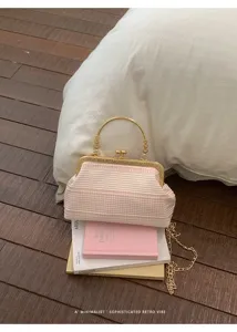 Vue détaillée du sac à main rétro à carreaux rose et blanc posé sur des livres.