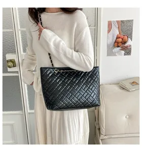Dettaglio della borsa nera trapuntata con tracolla a catena per un look molto chic.