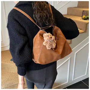 Detailaufnahme des retro braunen Rucksacks mit süßem Plüschanhänger, ideal für Herbststil.