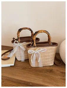 Gevlochten stro emmer tas detail weergave, bamboe handvat en parel strik voor zomer mode.