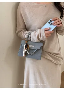 Stylish blue-grey Kelly handbag with beaded charm, elegant minimalist design for women.