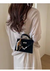 Vue détaillée d'un sac Kelly noir pour épaule avec charm de perles, style rétro chic.