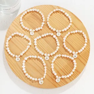 Freshwater pearl initial bracelet set with letter charms on wooden tray detail view
