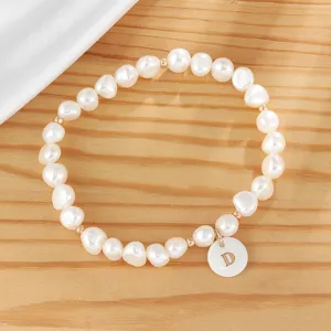 Freshwater pearl bracelet detail shot featuring a charming letter D pendant and gold beads.