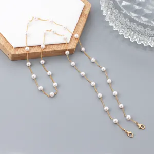 Detalle de primer plano de cadena dorada delicada con perlas, mascarilla o portagafas.