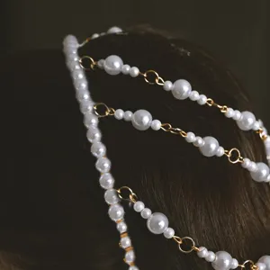 Detailed shot of a baroque pearl hair chain, featuring elegant multi-layer gold links for wedding.