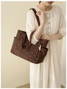 Detailansicht der braunen Damen Cord Tote Bag mit Erdbeerprint und praktischem Schultergurt.