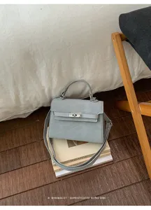 Détail de sac à main Kelly en cuir PU gris, poignée supérieure, fermoir métal et bandoulière.