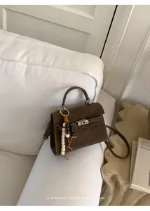 Sac à main Kelly marron vintage avec poignée et charm perlé chic pour les femmes.
