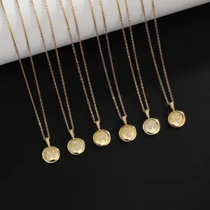 Detailed view of gold plated coin pendant necklace featuring sparkling rhinestone letters.