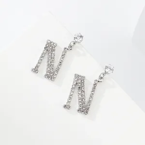 Primo piano dettagliato di orecchini pendenti con lettera N tempestata di brillanti strass.