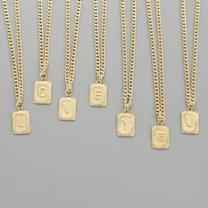 Detailed close-up view of gold initial pendant necklaces with stylish rectangular engraved charms.