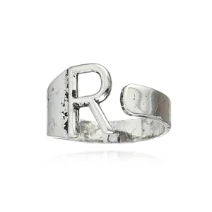 Gros plan détaillé de la bague ouverte en métal argenté vintage avec un design de lettre R.