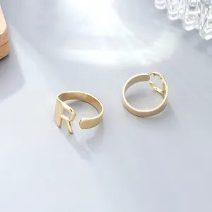 Gros plan sur une bague lettre R ouverte et dores minimaliste au design retro en cuivre.