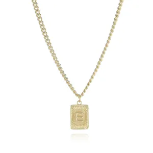 Gold initial necklace detail showing the rectangular pendant with letter E and chunky chain.