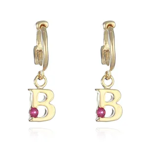 Detail shot of gold-plated letter B hoop earrings featuring a sparkling pink gemstone pendant.