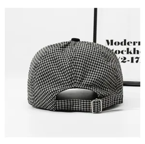 Black and white checkered duckbill cap detail showing adjustable metal buckle strap