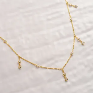 Close-up detail of gold body chain featuring dainty bezel-set rhinestone drop pendants.