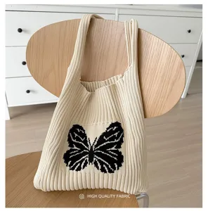 Detailed shot of knitted shoulder bag featuring a stylish black butterfly pattern.
