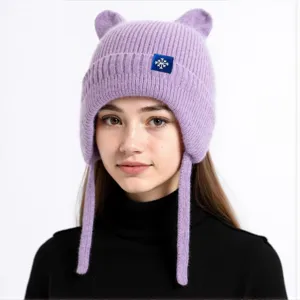 Niedliche lila gestrickte Mütze mit Ohrenklappen und geflochtenen Bändern für den Winter.