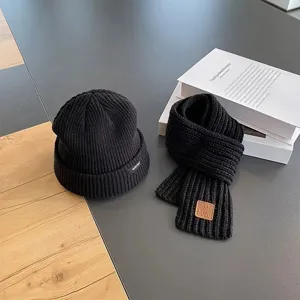 Black knitted beanie and scarf set detail, cozy winter woolen cap and soft scarf closeup.