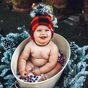 Dettaglio del cappello in maglia a quadri rossi e neri con pompon grande in un festivo bagno di latte.