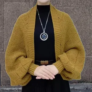 Close-up detail of yellow knit cardigan showing textured geometric pattern and loose sleeves.