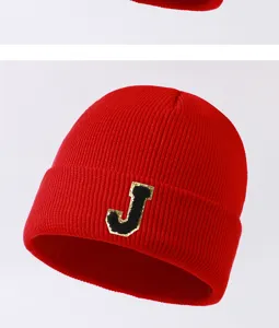Close-up detail shot of the red knitted beanie showcasing a stylish letter J patch design.