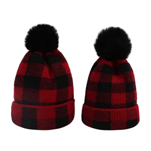 Cappello lavorato a maglia a quadri rosso e nero con dettaglio di pon pon in pelliccia.
