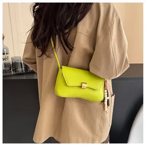 Vista di dettaglio della borsa a tracolla verde lime alla moda con chiusura metallica e ciondolo.