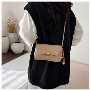 Borsa a tracolla chic minimalista in pelle con elegante serratura metallica e ciondolo di perle.