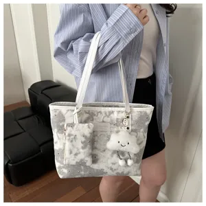 Close-up detail of grey star pattern tote bag with plush cloud pendant and mini pouch.