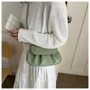 Green ruched flap saddle bag detail shot, chic commuter crossbody shoulder handbag.
