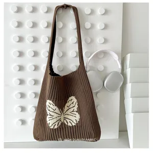 Detail view of brown knitted shoulder bag featuring a white butterfly pattern and soft wool feel.